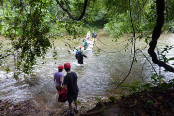 Group of visitors wading through a river in Belize