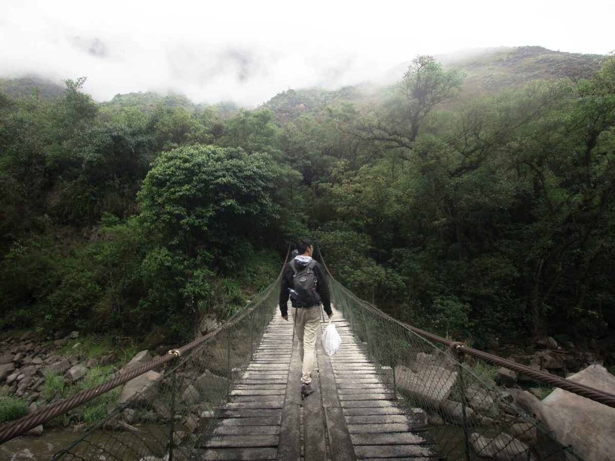 a person walking across a bridge hiking the Inca Trail to Machu Picchu