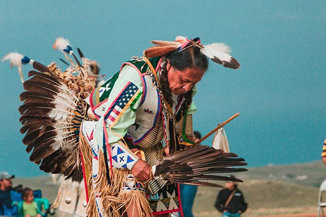 Native American in traditional outfit performing a ceremony