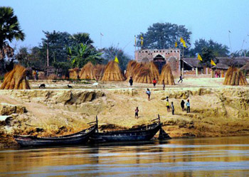 thatched huts on bank above Ganges river