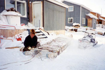 Inuit man repairing sled