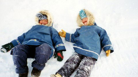 Two Inuit lying in the snow