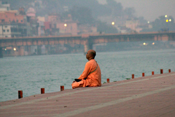 man meditating on steps above river