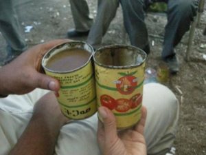 drinking tella out of old tin cans