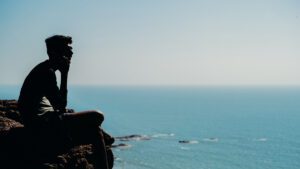 A man overlooking the sea from a rock in Goa.