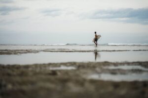 man carrying surfboard on beach