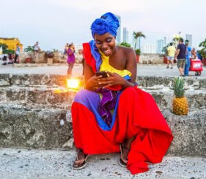 A Colombian woman in colorful clothes holding a phone.