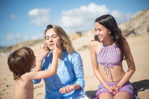 A child helping his mother put on sunscreen.