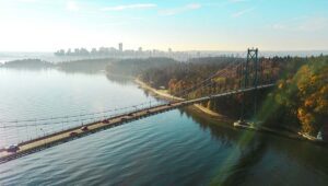 bridge leads into park with city skyscrapers in background