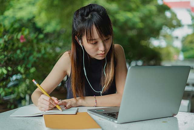 Asian woman using laptop in Internet cafe