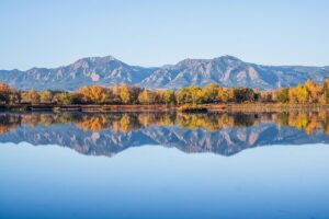 Scenic view of the Flatirons reflecting in a calm lake during autumn in Boulder, one of the best photography spots in the Rocky Mountains