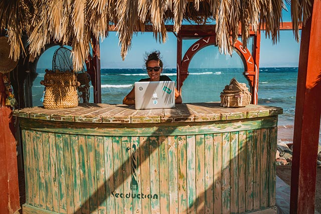 woman using laptop on beach